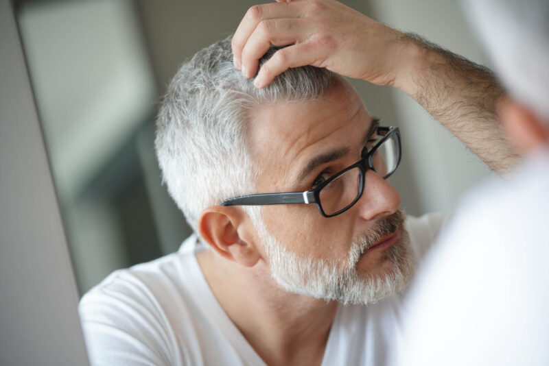 man checking his hair on front of a mirror