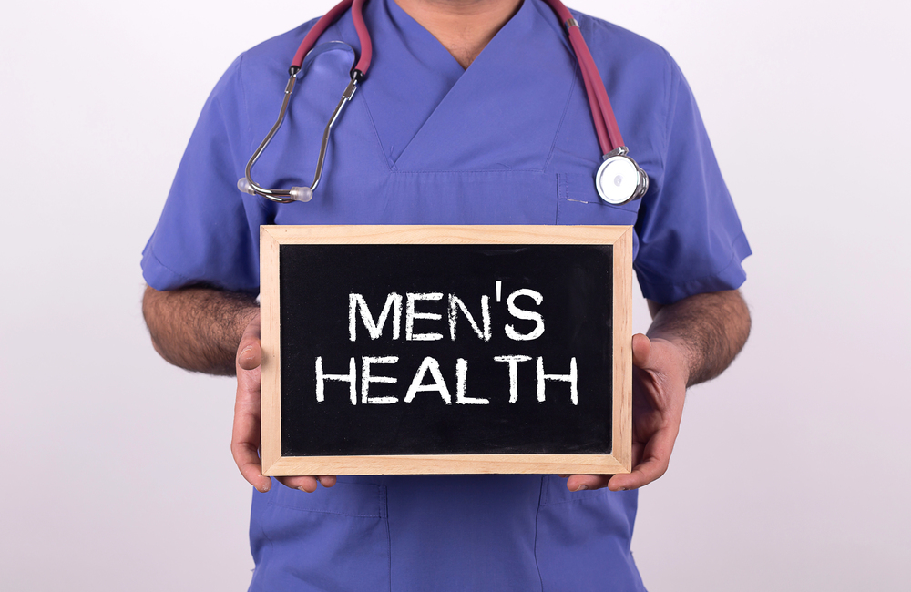 man holding a sign that says mens health