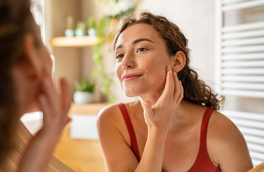 girl looking at mirror while touching her face and checking